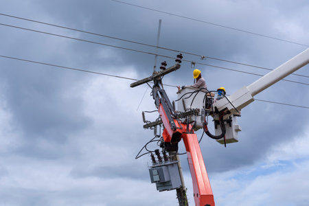 electrician works on bucket car to maintain high voltage transmission lines.の写真素材