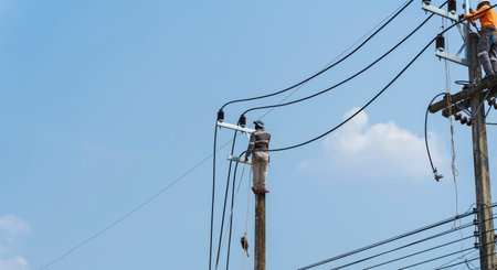 Electricians work on high voltage towers to install new wires and equipment.の写真素材