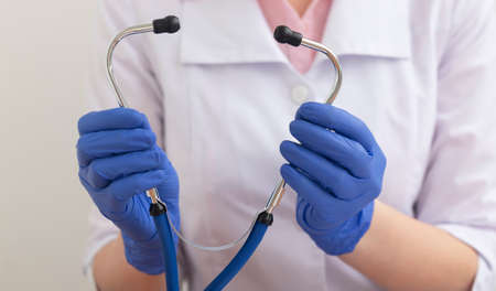 female doctor in gloves taking Stethoscope at doctor working table close up. Healthcare and medical concept.の写真素材