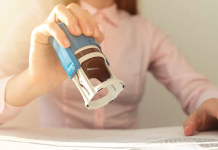Young businesswoman or notary public sitting at the desk in office and stamping document contract,...