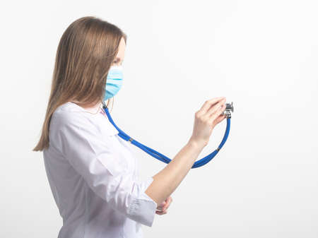 close up Portrait of caucasian doctor woman in face mask with stethoscope using in aside direction in clinic or hospital on white isolated background. doctor putting on stethoscopeの写真素材