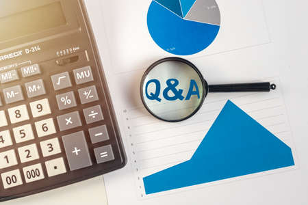 questions and answers concept - Q and A - magnifying glass on office table with calculator and blue color charts diagramsの写真素材