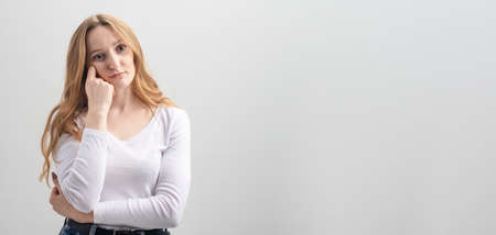 young bored woman posing on white background in studio, copy spaceの写真素材
