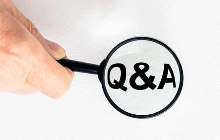 questions and answers concept - Q and A - magnifying glass in male hand, isolated on gray blue
