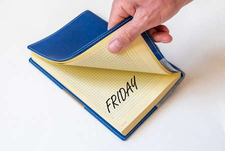 Note book with Friday word with male hand, white tableの写真素材