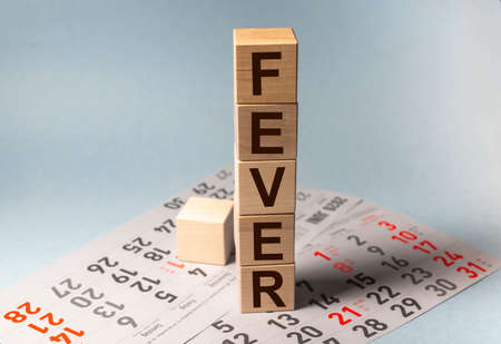 Fever - word made on wooden cubes on light blue backround. with calendar sheets, Healthy care and...