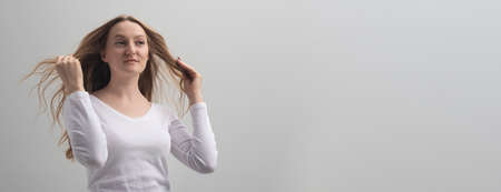 self-confident surprised young woman admire herself and touching her long hair. She is sure that she is the best, narcissism and self-admiration. gray background, studio, copy spaceの写真素材