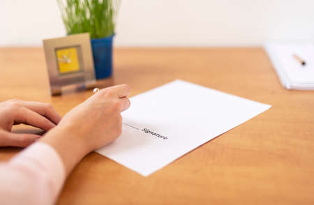 close up woman hand hold golden pen sign contract put signature, make investment, taking insurance, writing will testament, office table close upの写真素材