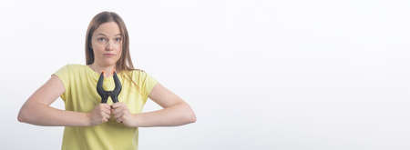 Young caucasian woman holding clamps over white background, studio shot, copy space, bannerの写真素材