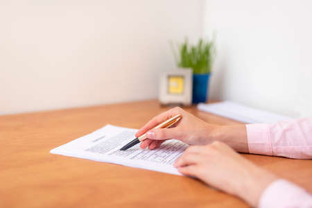 Close up hand business woman at the table in office. Concept of business contract studying reading and signing, business officeの写真素材