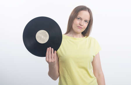 young smiling and calm woman holding vinyl records on a white background in studio. music conceptの写真素材