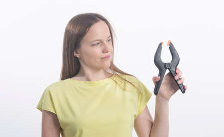 Young caucasian woman holding clamps over white background, studio shot