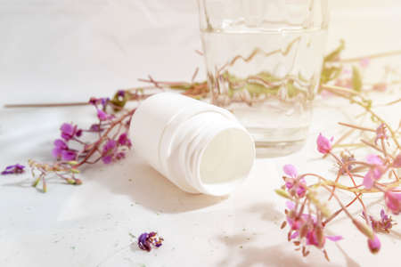 Jar of pills, glass of water and herbs instead of pills on a light white background The concept of health and cure by herbs or pills, medicalの写真素材