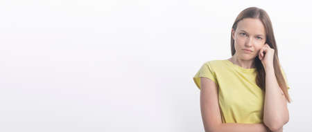Portrait of a young woman on a white background. serious woman looking at camera attentively with hand near ear, studio, copy space, bannerの写真素材
