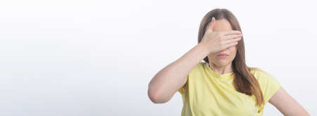 young woman closing her eyes with hand over white background, studio, copy space, bannerの写真素材