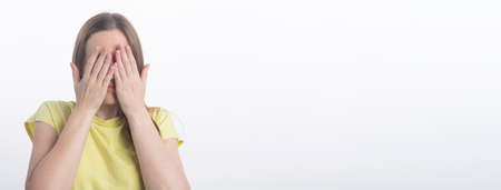 young woman closing her eyes with both hands over white background, studio, copy space, banner