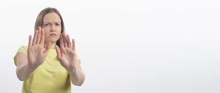Portrait of a beautiful girl showing stop sign with palms isolated on a white background, both hands to camera, copy space, bannerの写真素材
