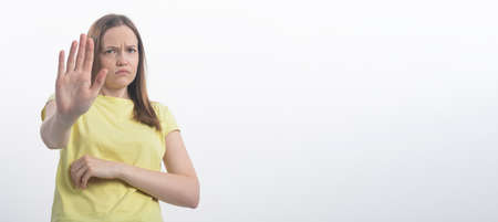 Portrait of a beautiful girl showing stop sign with palms isolated on a white background, hand to camera, copy space, bannerの写真素材