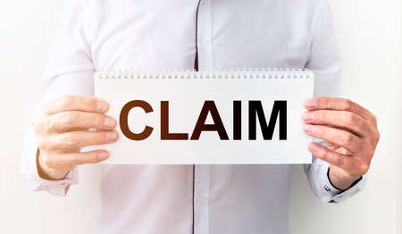 Businessman holding a paper card with text Claim in hand, lawsuit and claim conceptの写真素材