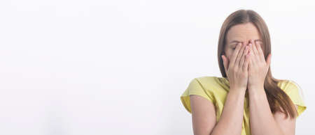young woman closing her eyes with both hands over white background, studio, copy space, bannerの写真素材