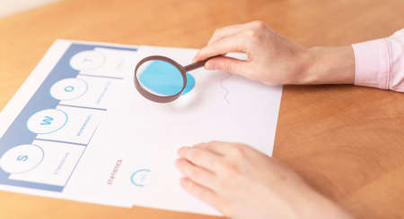 Strength Weaknesses Opportunities Threats Analysis Evaluation Strategy Concept. blue SWOT chart on office table with female hands with pen, marketing strategy, businessの写真素材