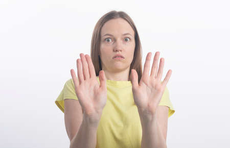 Portrait of a beautiful girl showing stop sign with palms isolated on a white background, both hands to cameraの写真素材