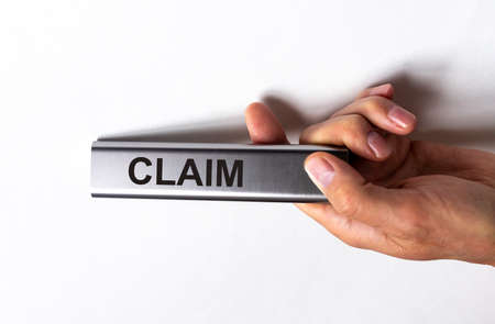 Claim word on silver remote control in male hand on white background, submission of claimの写真素材