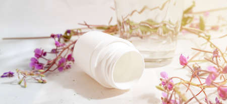 Jar of pills, glass of water and herbs instead of pills on a light white background The concept of health and cure by herbs or pills, medical, bannerの写真素材