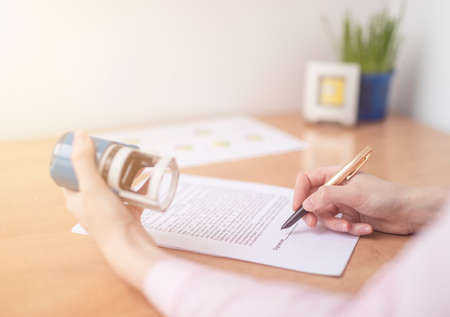 Businesswoman is signing a contract at office table with folders, stamp and contract, signing agreement close upの写真素材