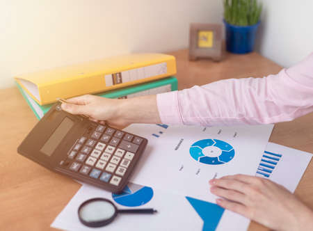 Insurance concept. female hands at office table with blue charts documents, Real Estate concept. analyzing insurance policyの写真素材