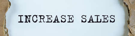 Increase sales inscription text written on white office table through torn craft paper.の写真素材