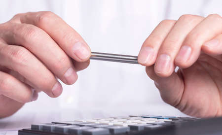 financial analysis concept, male hands holding pen and using a calculator over accounting documents. close upの写真素材