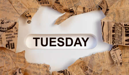 text tuesday on on white table through torn paper.の写真素材