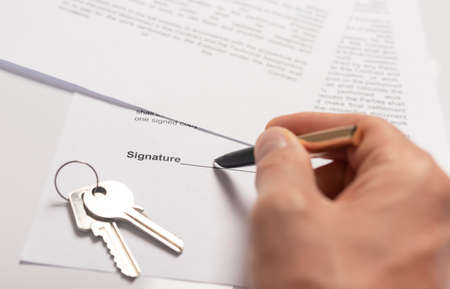 Businessman signing contract with keys on table. real estate agreement concept.