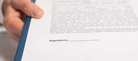 Businessman reaching out documents to camera and offering to sign them. close up bannerの写真素材