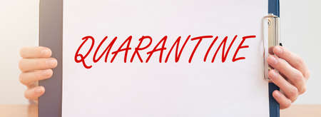 word QUARANTINE on paper in hands of doctor in protective gloves over white background. medical lockdown concept, banner close upの写真素材