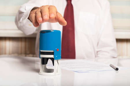 stamping document in office, male hand spreading to seal for verifying document.