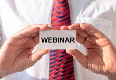 word Webinar on paper card in businessman hands.