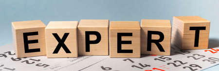 expert word written on wooden blocks on blue office table with calendar sheets, bannerの写真素材