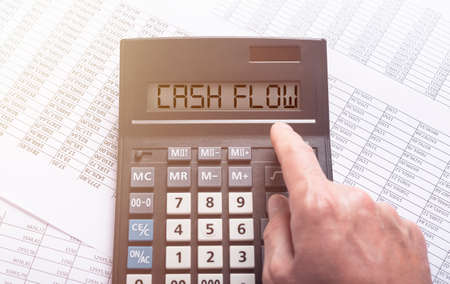 CASH FLOW word on calculator on financial documents with male hand, top view, flatlyの写真素材