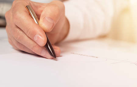Contract signing concept. Businessman hand with pen over document closeup.