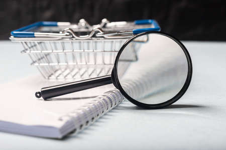 office table with magnifying glass and shopping basket blurred close up, warehouse and trading conceptの写真素材
