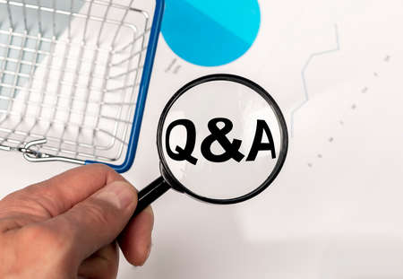 magnifier with text Q and A and business analytical documents and shopping basket on table, flatlyの写真素材