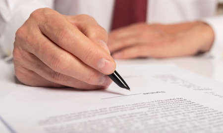 Contract signing concept. Businessman hand with pen over document closeup.の写真素材