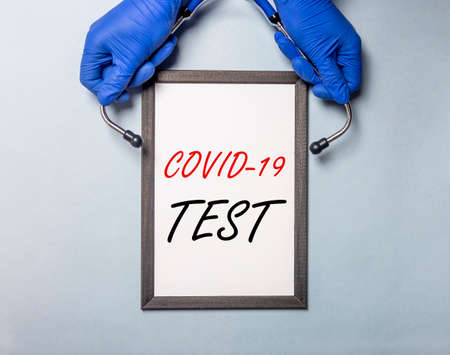 COVID-19 test inscription. Coronavirus concept on table with doctor hands in gloves, top view.
