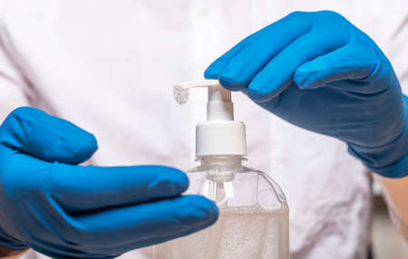 Male hands in glove applying or using sanitizer for hands disinfection during pandemic. Sanitizing...