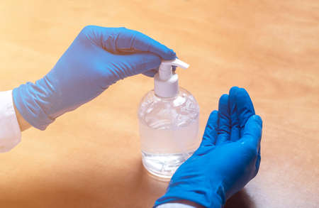 Male hands in glove applying or using sanitizer for hands disinfection during pandemic. Sanitizing...