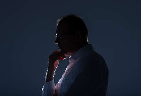 Pensive thinking businessman profile with hand at chin.