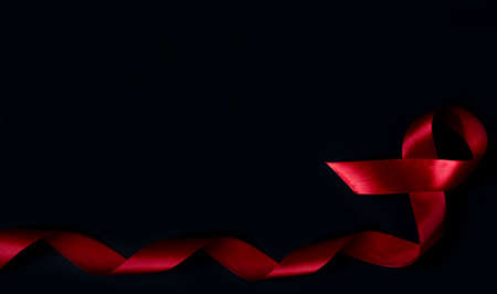 World aids day concept. Red ribbon isolated on black background. Banner with copy space.の写真素材