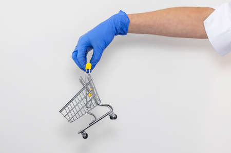 Shopping metal empty cart in male hand in blue protecive glove. shopping during coronavirus lockdown concept.の写真素材